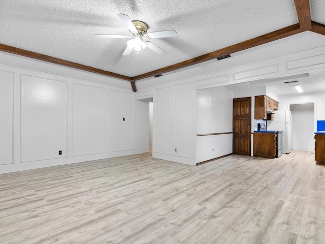 unfurnished living room with beam ceiling, a textured ceiling, and light hardwood / wood-style floors