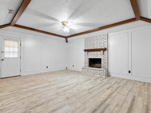 unfurnished living room featuring lofted ceiling with beams, a textured ceiling, a fireplace, and light hardwood / wood-style floors