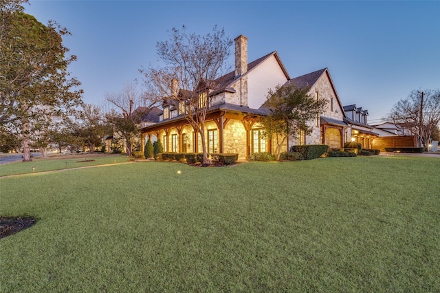 property exterior at dusk featuring a lawn