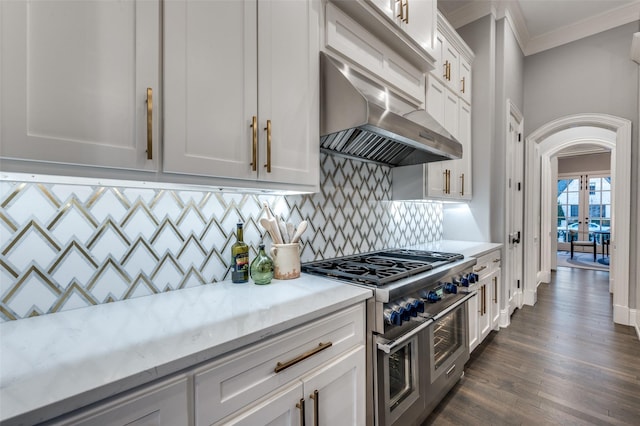 kitchen featuring backsplash, white cabinets, double oven range, exhaust hood, and crown molding