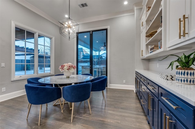 dining space featuring dark wood-type flooring, ornamental molding, and an inviting chandelier