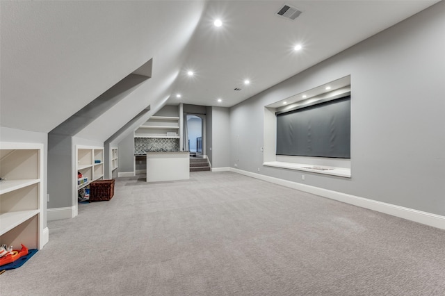 bonus room featuring light carpet, built in shelves, and vaulted ceiling