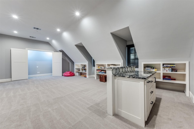 interior space featuring lofted ceiling, light colored carpet, and built in features