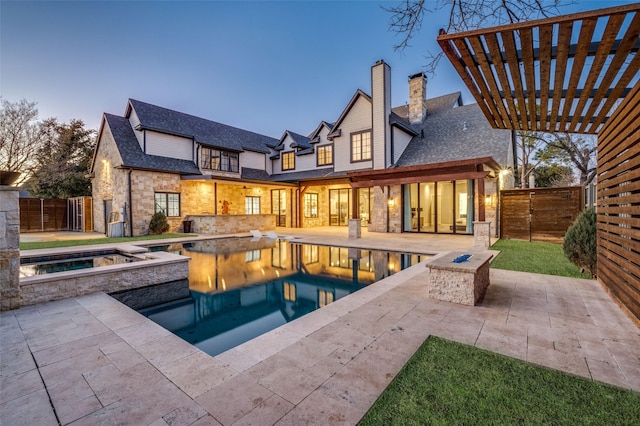 back house at dusk with a pool with hot tub, a pergola, a patio area, and a fire pit