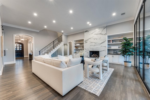 living room with a premium fireplace, dark hardwood / wood-style floors, built in features, and ornamental molding