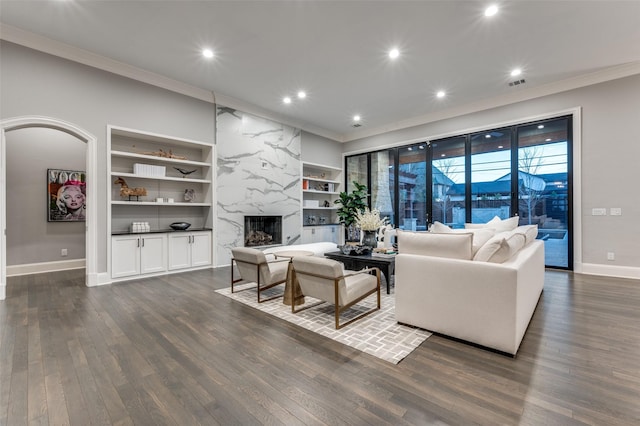 living room with a premium fireplace, dark hardwood / wood-style floors, crown molding, and built in shelves