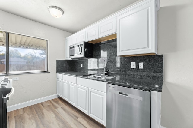 kitchen featuring stainless steel appliances, white cabinetry, sink, and backsplash