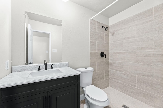 bathroom featuring vanity, toilet, and a tile shower