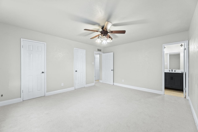 unfurnished bedroom with ceiling fan, sink, light carpet, and ensuite bath