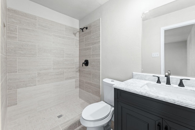 bathroom with vanity, toilet, and a tile shower