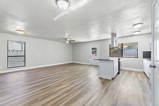 kitchen featuring island range hood, light wood-type flooring, a textured ceiling, and white cabinets