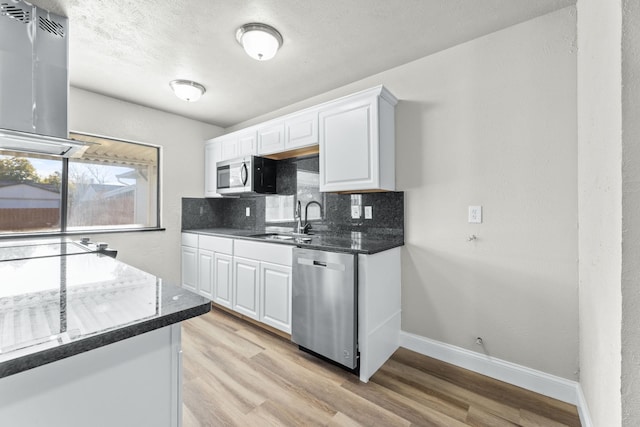 kitchen featuring white cabinetry, sink, island exhaust hood, and appliances with stainless steel finishes