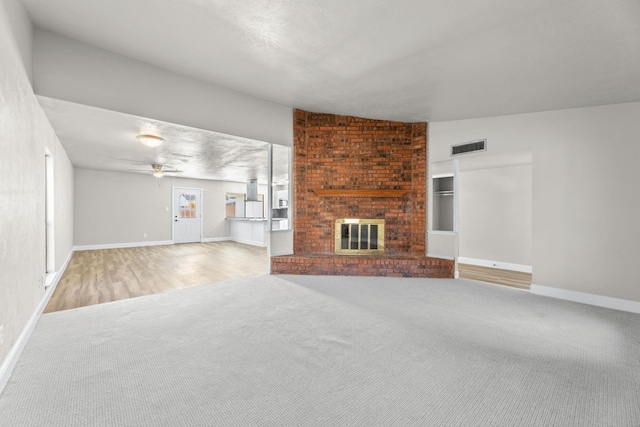 unfurnished living room with carpet floors, a fireplace, and ceiling fan