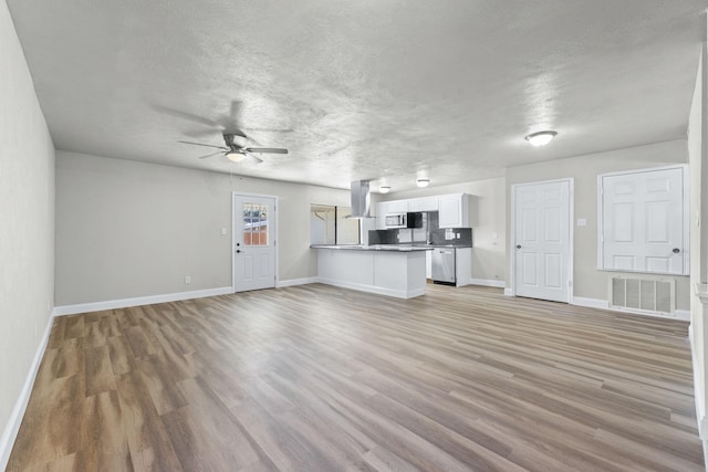 unfurnished living room featuring ceiling fan, wood-type flooring, and a textured ceiling