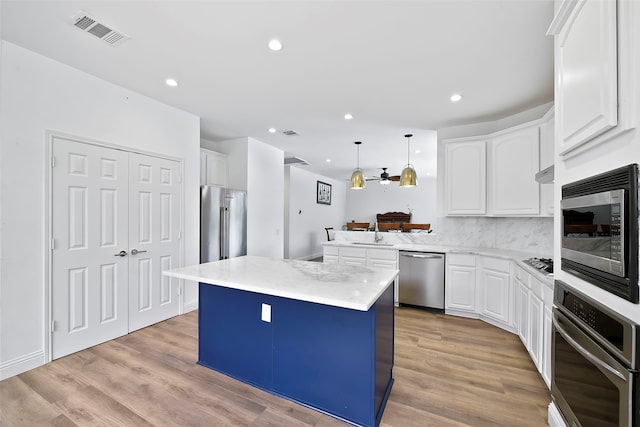 kitchen with a center island, hanging light fixtures, kitchen peninsula, stainless steel appliances, and white cabinets