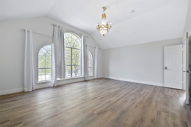 interior space featuring hardwood / wood-style flooring, vaulted ceiling, a wealth of natural light, and an inviting chandelier