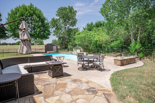 view of patio with a storage unit, a fenced in pool, and an outdoor living space with a fire pit