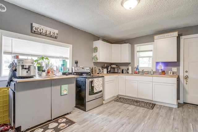 kitchen with white cabinetry, sink, light hardwood / wood-style floors, and electric stove