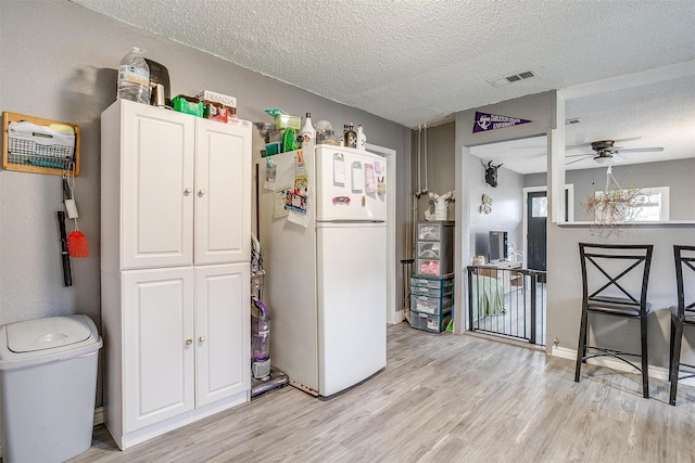 kitchen featuring ceiling fan, light wood-type flooring, a textured ceiling, and white refrigerator