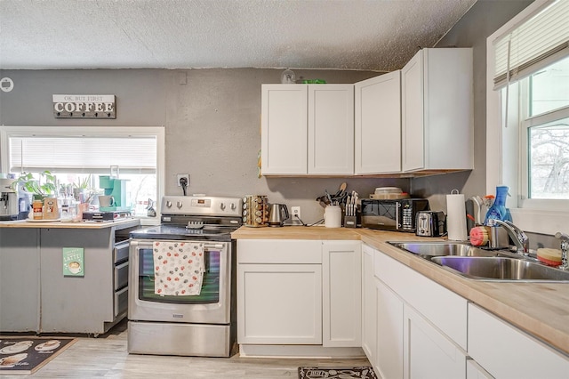 kitchen featuring white cabinetry, sink, electric range, and wooden counters