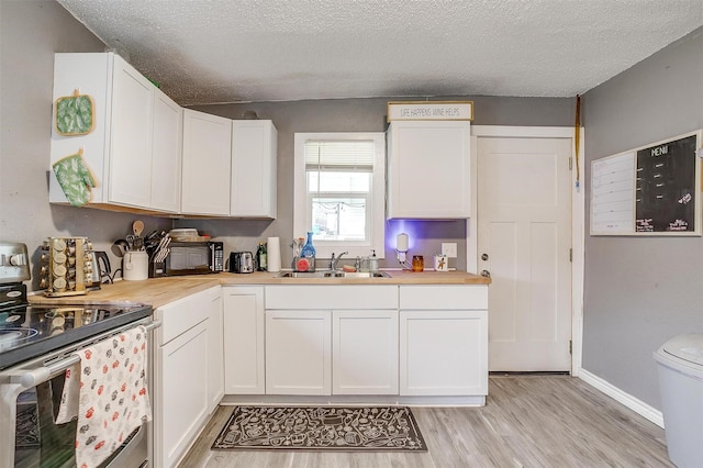 kitchen with white cabinetry, sink, stainless steel electric range, and light wood-type flooring