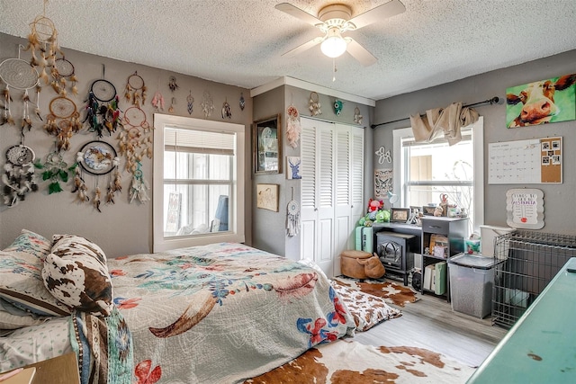 bedroom featuring ceiling fan, hardwood / wood-style floors, a closet, and a textured ceiling