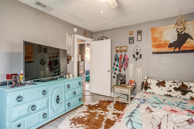 bedroom with ceiling fan, hardwood / wood-style flooring, and a textured ceiling