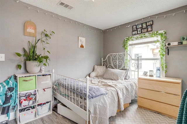 bedroom with a textured ceiling and light wood-type flooring