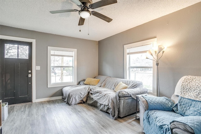 living room featuring ceiling fan, light hardwood / wood-style floors, and a textured ceiling