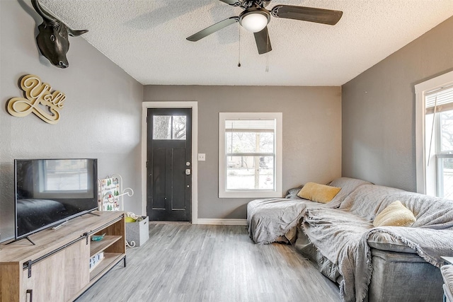 living room with ceiling fan, a healthy amount of sunlight, light hardwood / wood-style flooring, and a textured ceiling