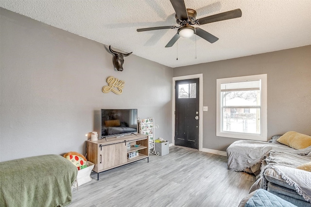 bedroom featuring ceiling fan, light hardwood / wood-style floors, and a textured ceiling