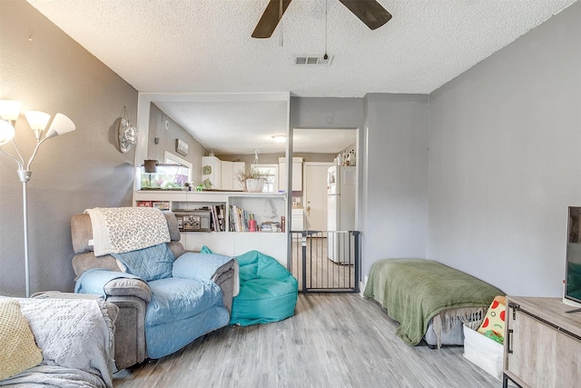 living room with ceiling fan, light hardwood / wood-style floors, and a textured ceiling