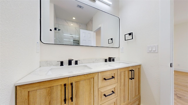 bathroom featuring hardwood / wood-style flooring, vanity, and a shower