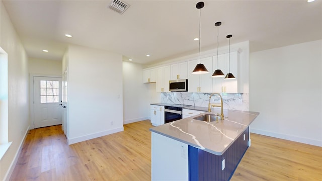 kitchen featuring white cabinetry, sink, decorative light fixtures, and appliances with stainless steel finishes