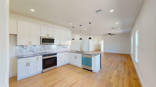 kitchen with sink, appliances with stainless steel finishes, white cabinetry, decorative light fixtures, and kitchen peninsula