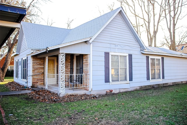 view of side of property featuring a porch and a lawn