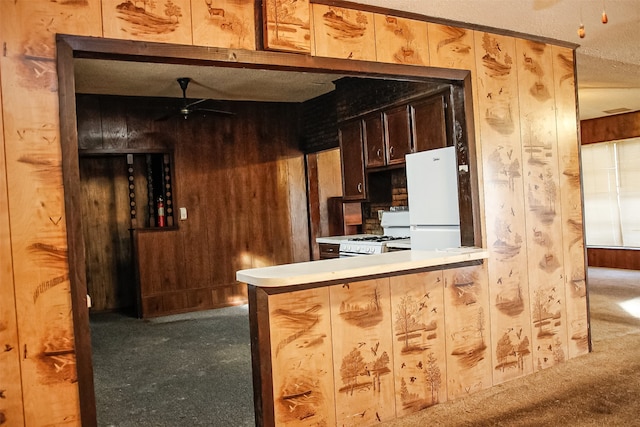 kitchen with carpet flooring, white appliances, ceiling fan, and wood walls