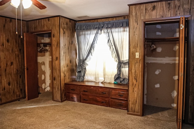 bedroom featuring wooden walls, ornamental molding, ceiling fan, and carpet