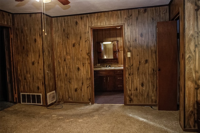 interior space with ornamental molding, wooden walls, connected bathroom, and dark carpet