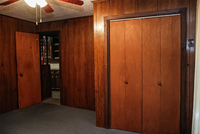 interior space featuring carpet flooring, a textured ceiling, and wood walls