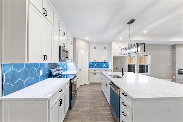 kitchen featuring white cabinetry, sink, stainless steel appliances, and a center island with sink