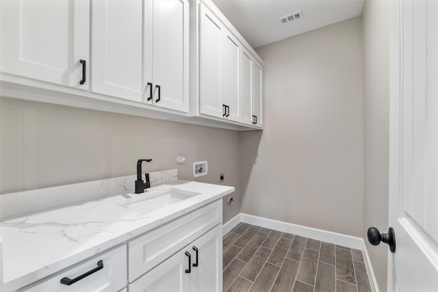 clothes washing area with electric dryer hookup, sink, hookup for a washing machine, and cabinets