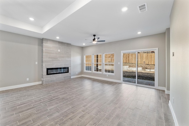 unfurnished living room featuring ceiling fan, a fireplace, and light wood-type flooring