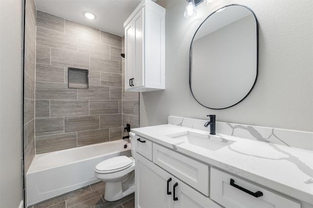 full bathroom with tiled shower / bath, vanity, and toilet