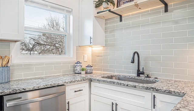 kitchen with white cabinetry, stainless steel dishwasher, light stone countertops, and sink