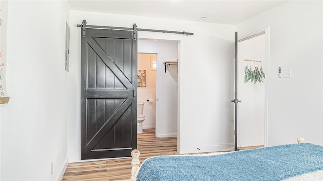 bedroom with hardwood / wood-style flooring and a barn door