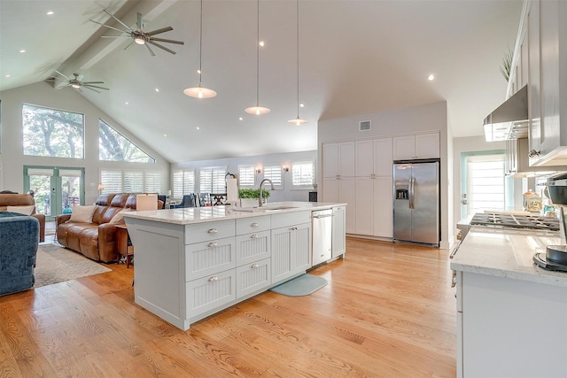 kitchen featuring wall chimney exhaust hood, stainless steel appliances, an island with sink, and white cabinets