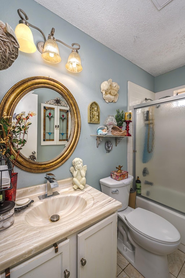 full bathroom featuring combined bath / shower with glass door, tile patterned flooring, vanity, a textured ceiling, and toilet