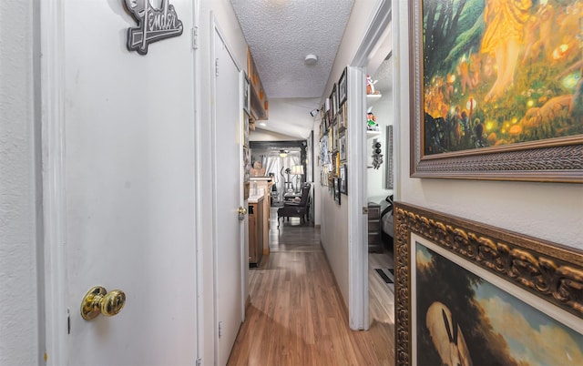 corridor featuring light hardwood / wood-style flooring and a textured ceiling