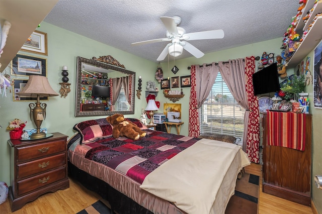 bedroom with ceiling fan, light hardwood / wood-style floors, and a textured ceiling